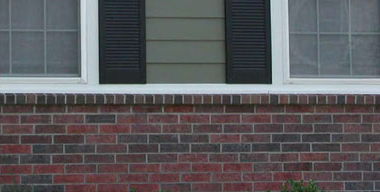 side of a residential building with brick siding uninterrupted by a window